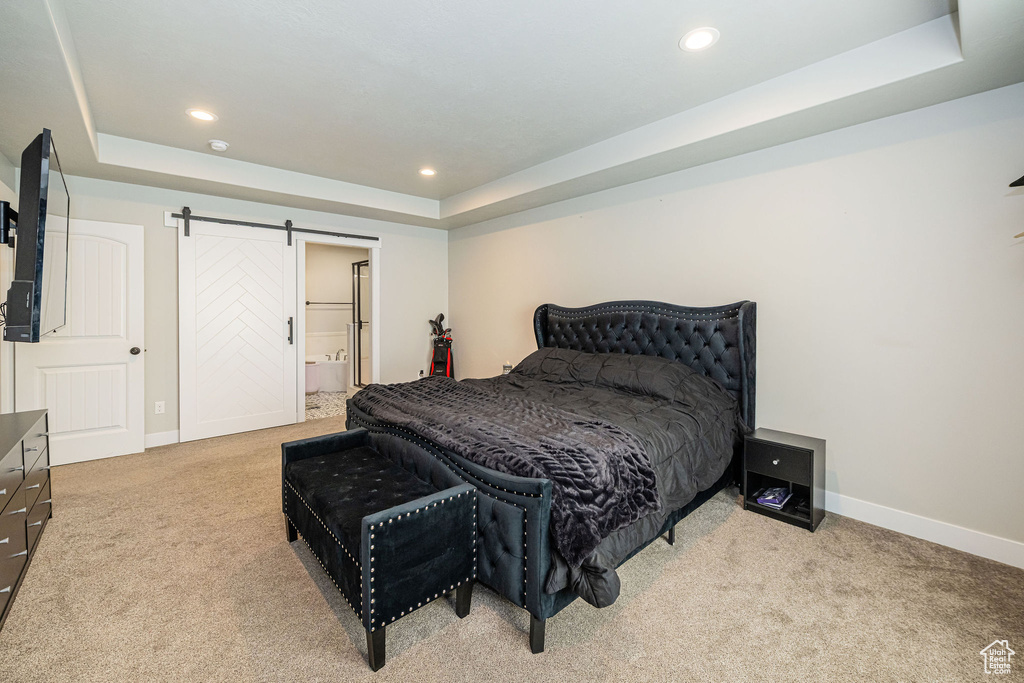 Bedroom with a tray ceiling, carpet floors, a barn door, and recessed lighting