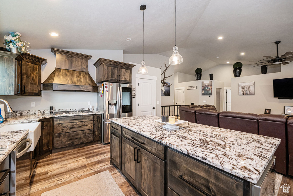 Kitchen with premium range hood, appliances with stainless steel finishes, vaulted ceiling, light stone countertops, and ceiling fan