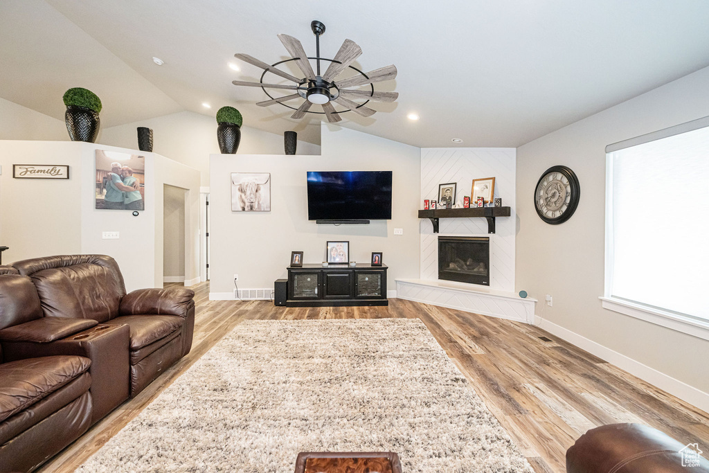 Living area with a ceiling fan, lofted ceiling, wood finished floors, a fireplace, and recessed lighting