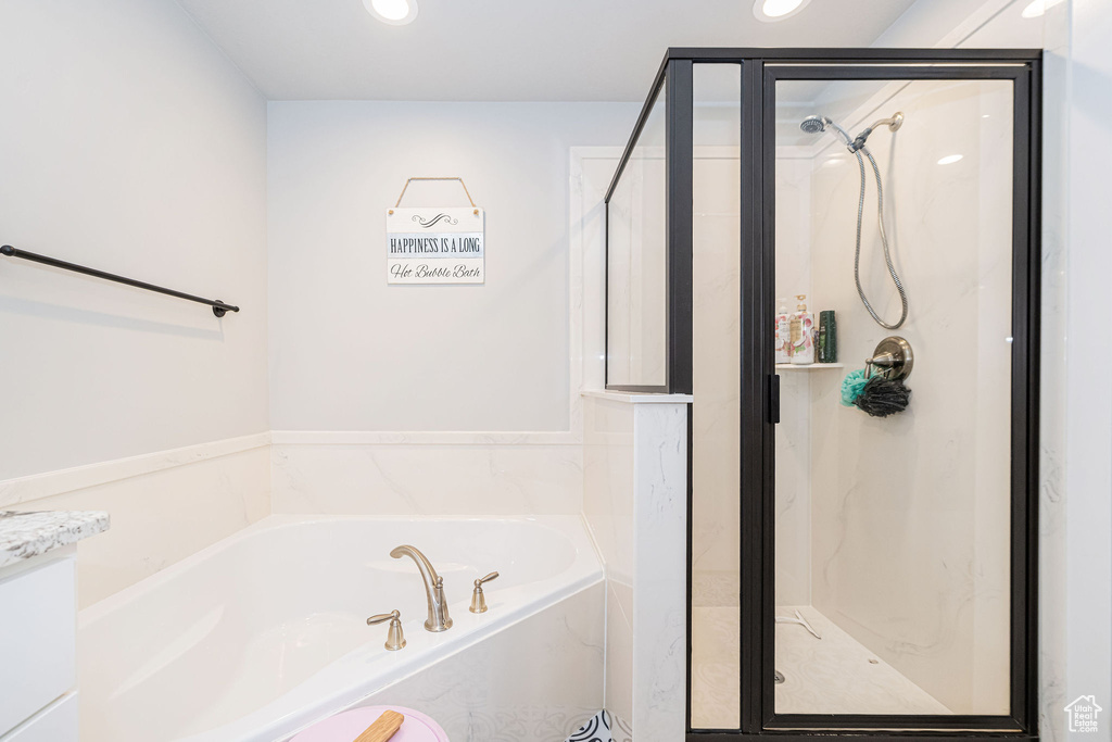Bathroom with a marble finish shower, a bath, and recessed lighting