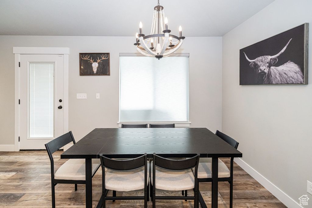 Dining room with a chandelier, wood finished floors, and healthy amount of natural light