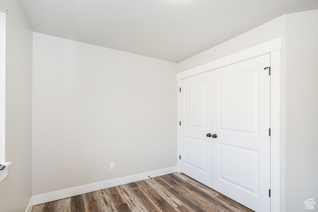 Unfurnished bedroom featuring dark wood finished floors and a closet