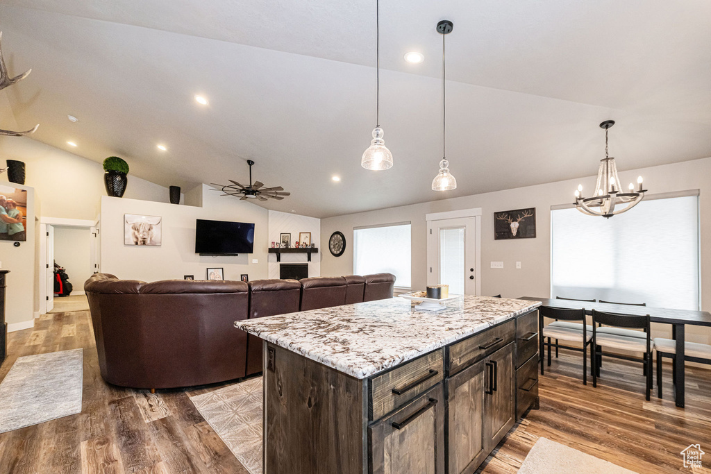 Kitchen featuring lofted ceiling, wood finished floors, a ceiling fan, pendant lighting, and recessed lighting