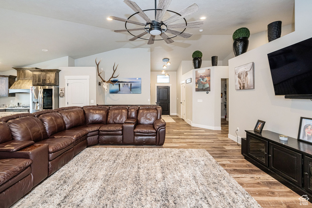 Living area featuring a ceiling fan, vaulted ceiling, light wood finished floors, and recessed lighting