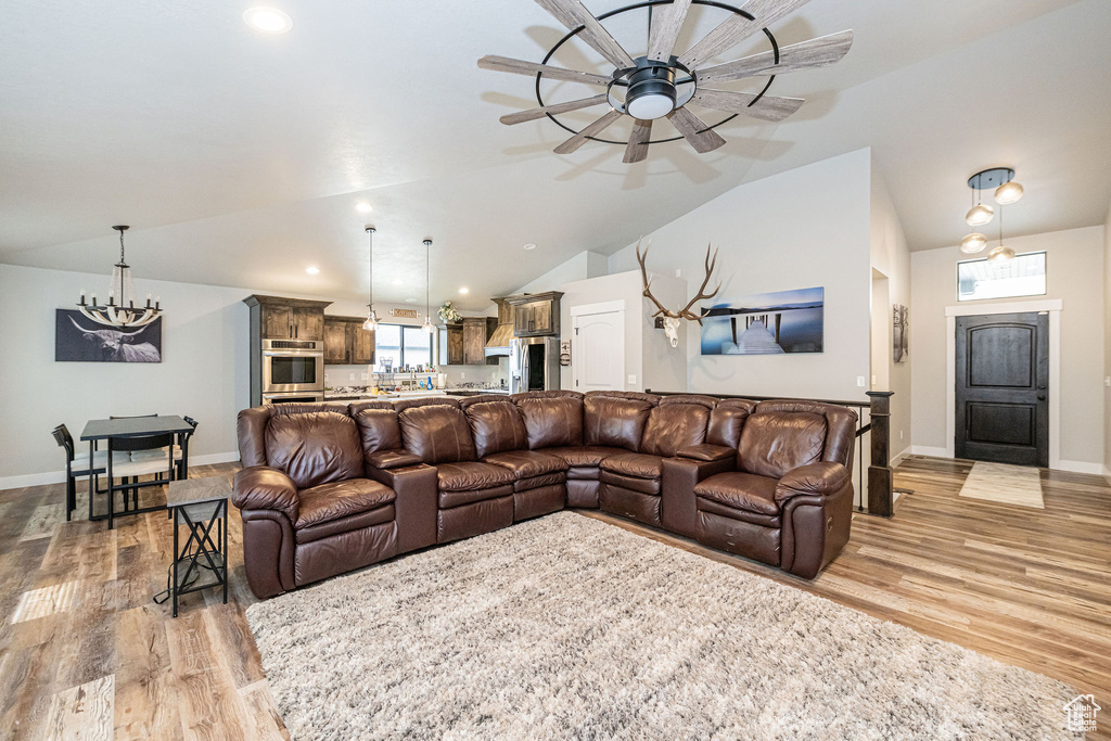 Living area featuring light wood-style floors, ceiling fan, lofted ceiling, a chandelier, and recessed lighting