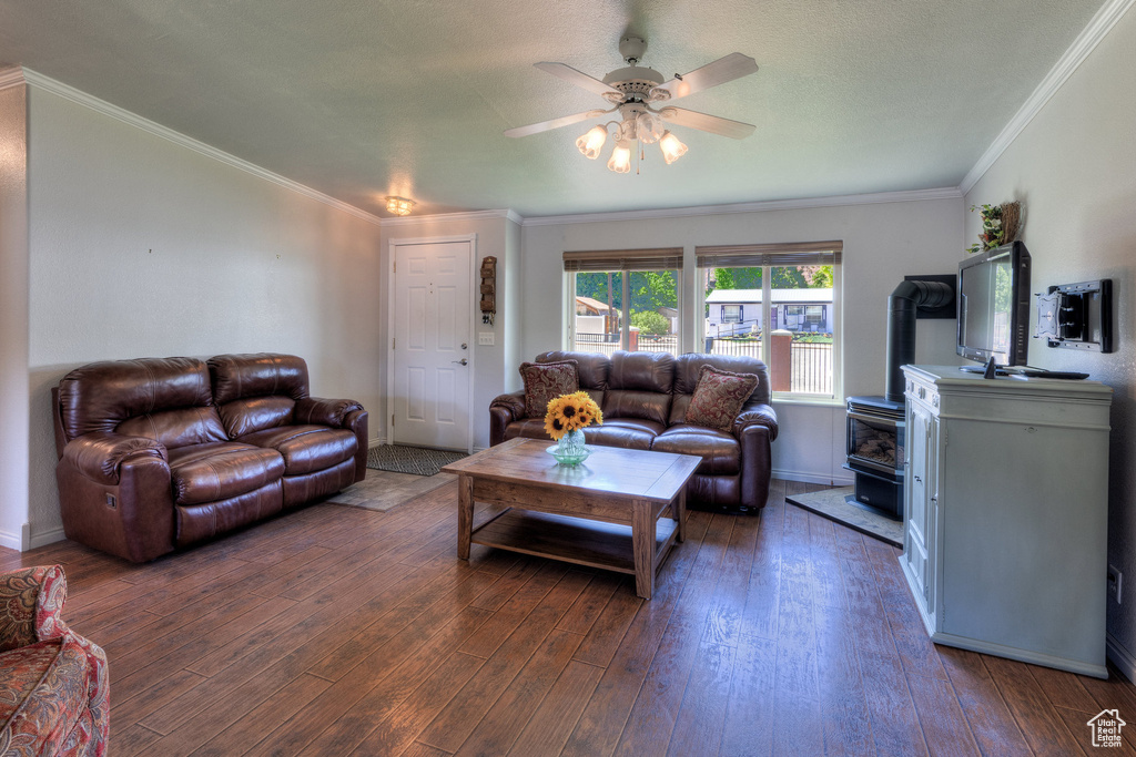 Living area featuring a wood stove, ceiling fan, wood-type flooring, and ornamental molding