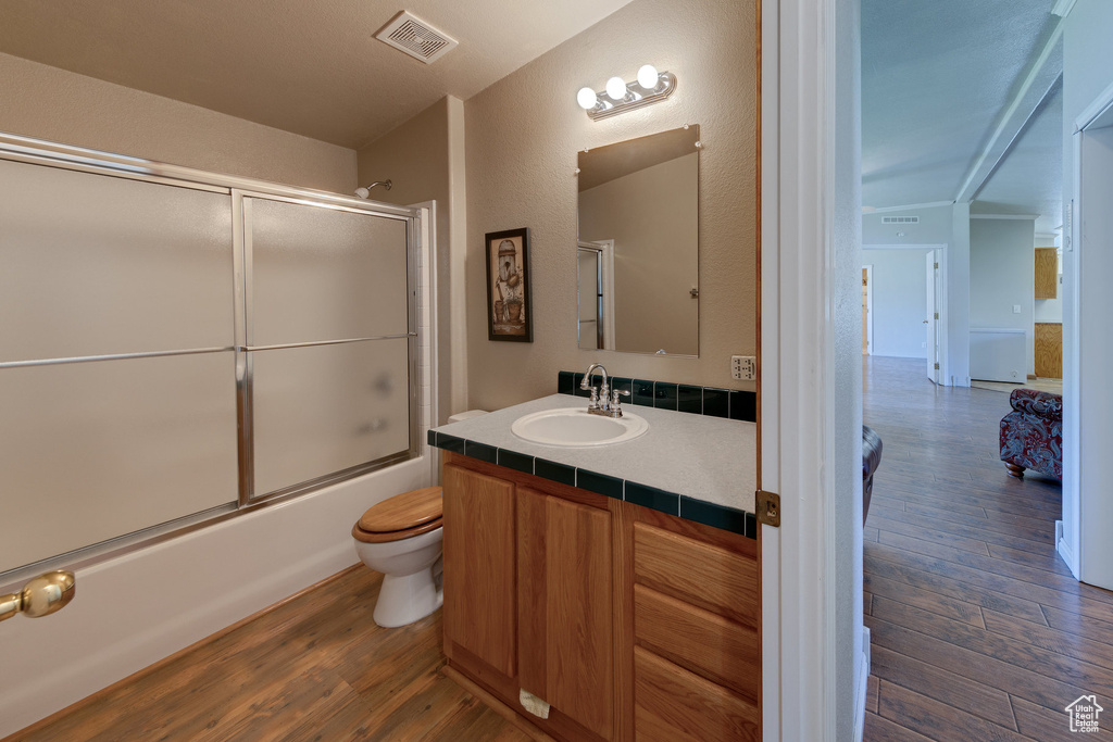Full bathroom featuring wood finished floors, vanity, and enclosed tub / shower combo