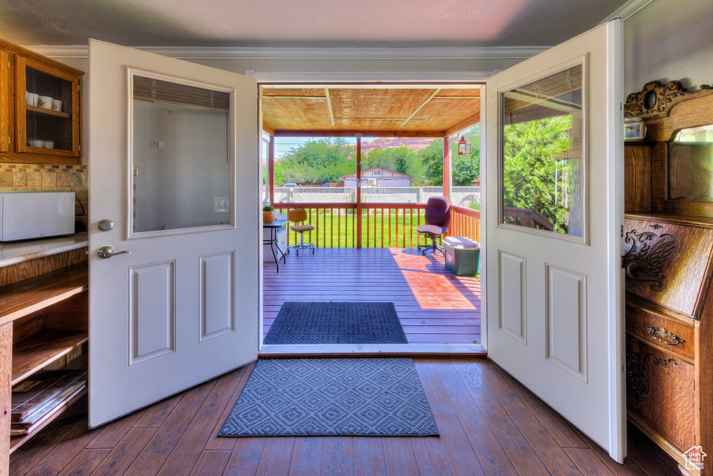 Doorway to outside featuring dark wood-style flooring and ornamental molding