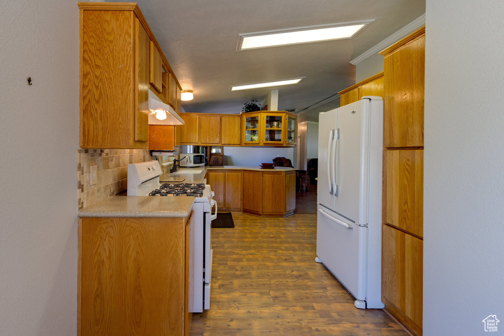 Kitchen with white appliances, brown cabinets, tasteful backsplash, dark wood finished floors, and light countertops