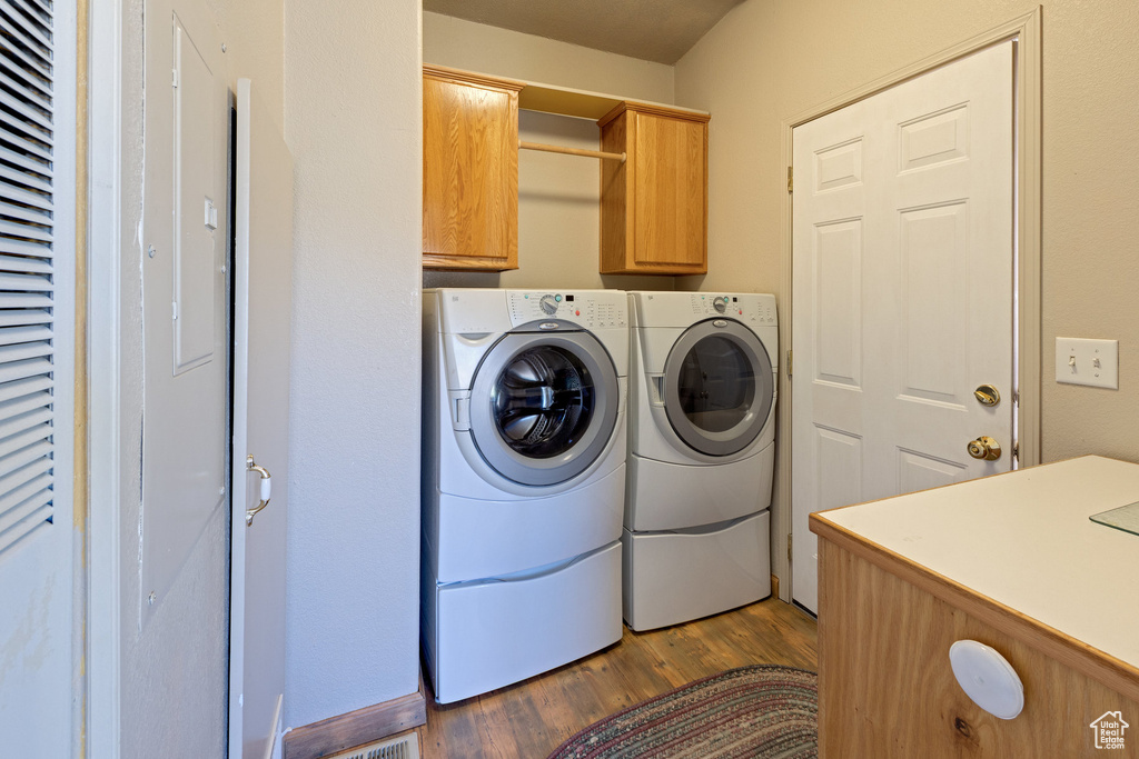 Laundry room with cabinet space, washer and clothes dryer, and wood finished floors