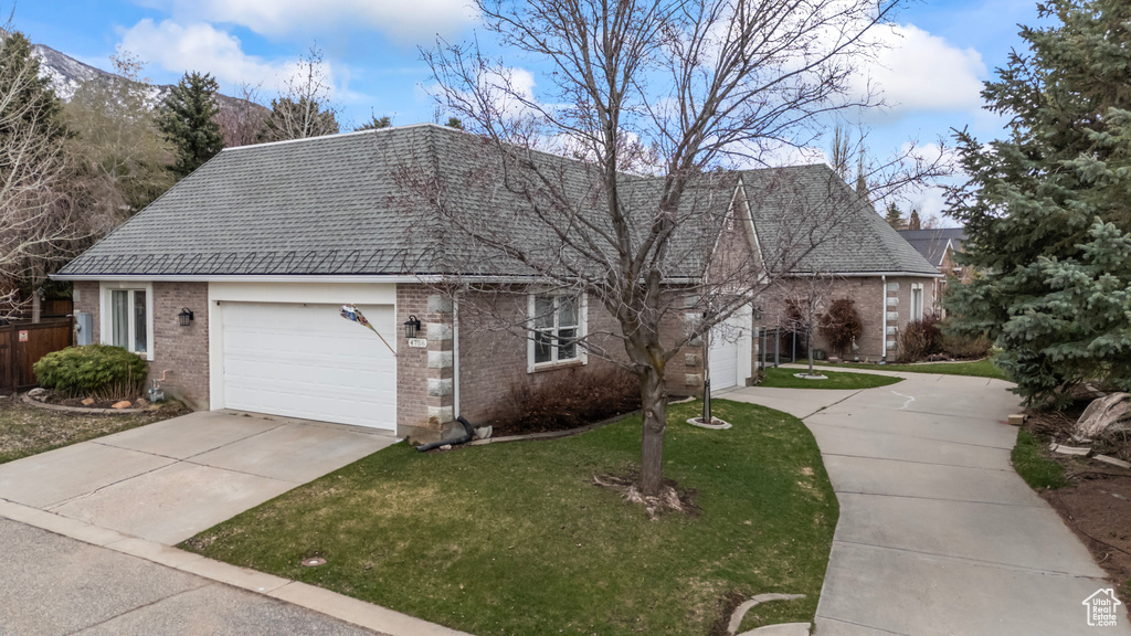 View of front facade featuring brick siding, driveway, a front lawn, and a garage