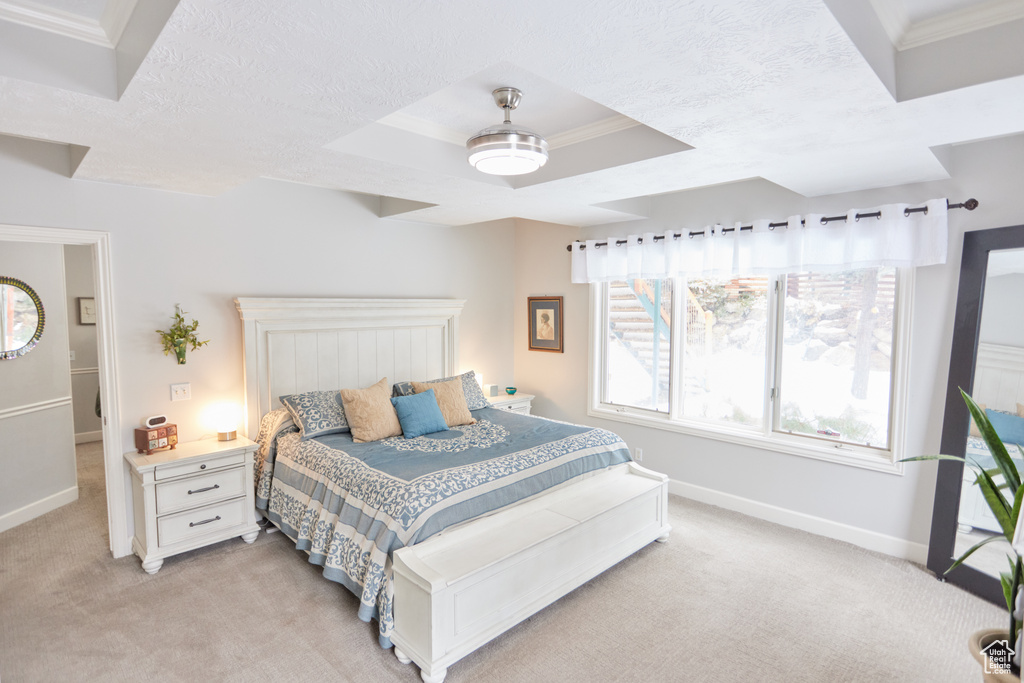 Bedroom with light colored carpet, crown molding, a raised ceiling, ceiling fan, and a textured ceiling