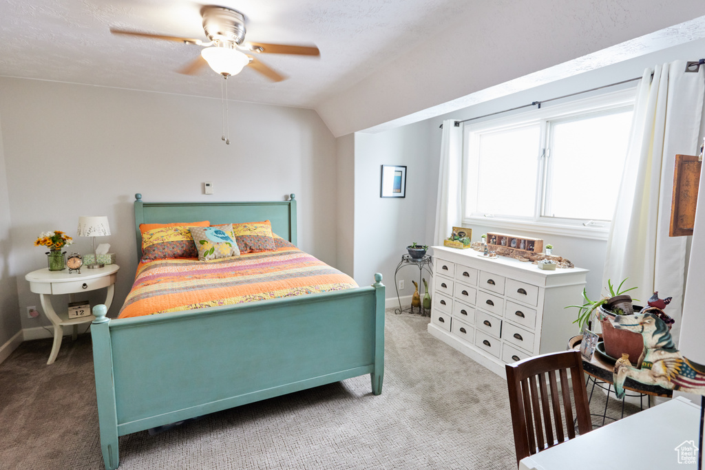 Carpeted bedroom featuring vaulted ceiling and a ceiling fan