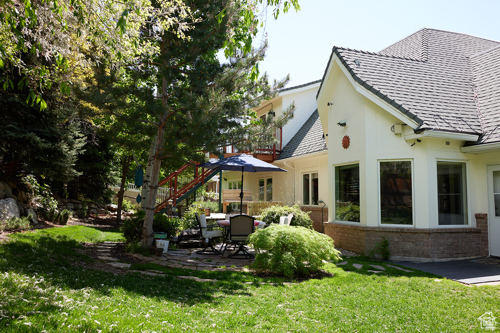 Rear view of house with a patio area, a yard, brick siding, and stucco siding