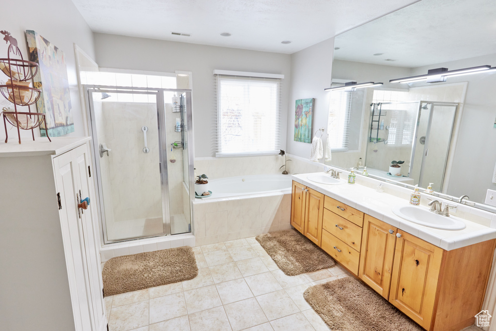 Full bath featuring a bath, a stall shower, double vanity, and tile patterned flooring