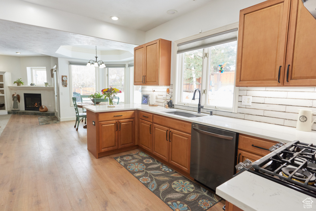 Kitchen with dishwasher, light countertops, a peninsula, light wood-style flooring, and recessed lighting