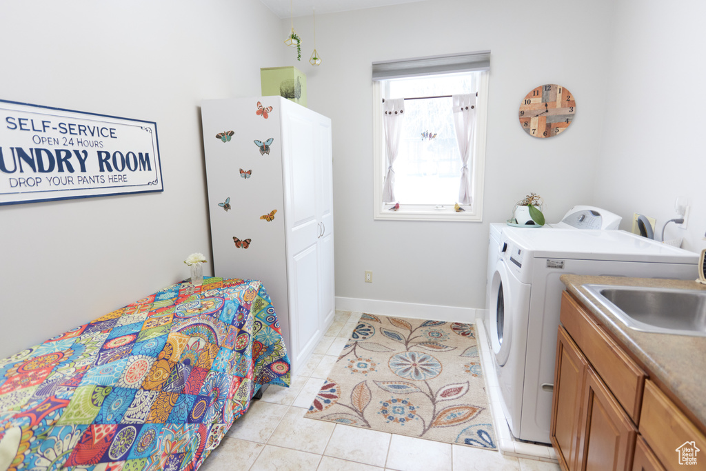 Laundry room with independent washer and dryer, light tile patterned floors, and cabinet space