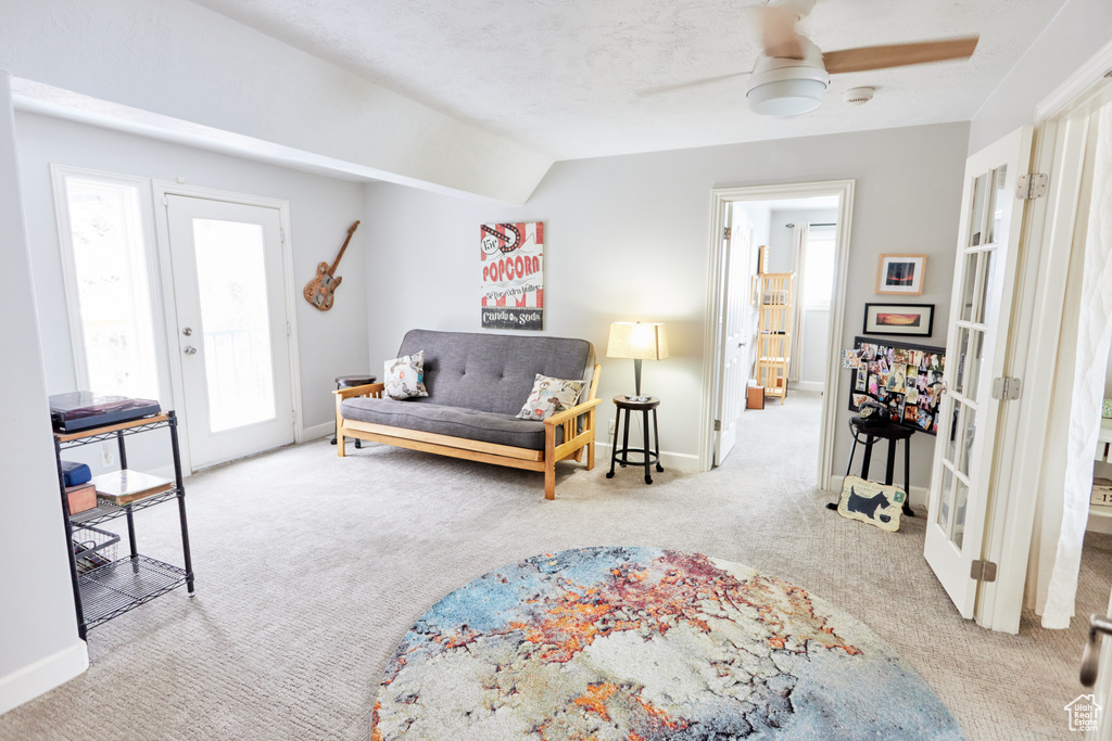 Carpeted living area with a ceiling fan, french doors, and vaulted ceiling