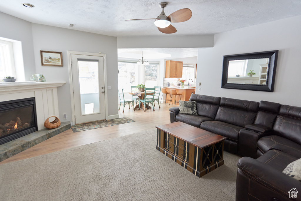 Living room with a ceiling fan, light wood-style floors, and a glass covered fireplace