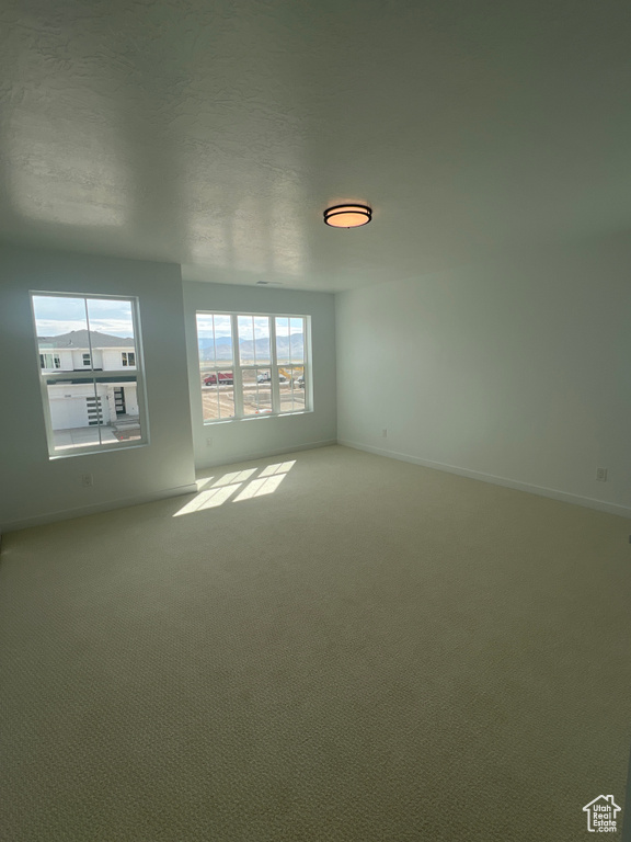 Carpeted spare room featuring baseboards