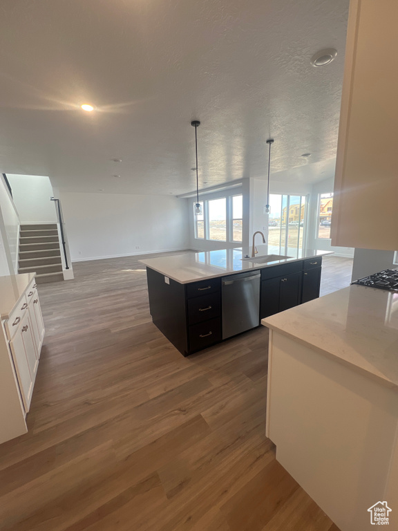 Kitchen featuring dishwasher, open floor plan, dark cabinets, and wood finished floors