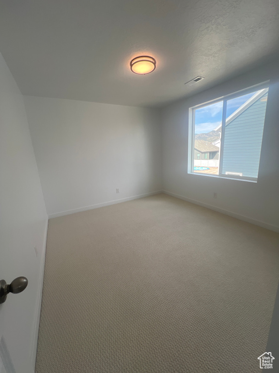 Empty room featuring light colored carpet and baseboards