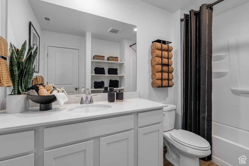 Full bath with vanity, shower / bath combo, and wood finished floors