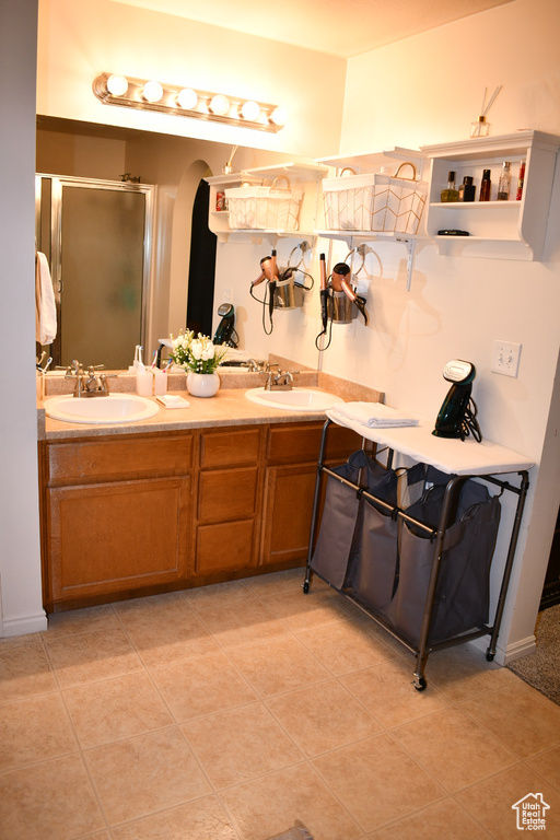 Full bath featuring double vanity, a stall shower, and tile patterned flooring