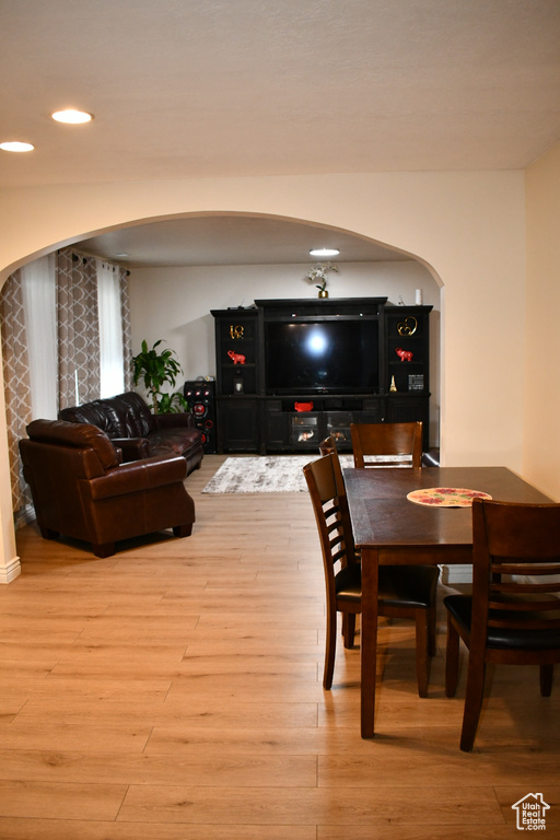 Dining space featuring arched walkways, wood finished floors, and recessed lighting