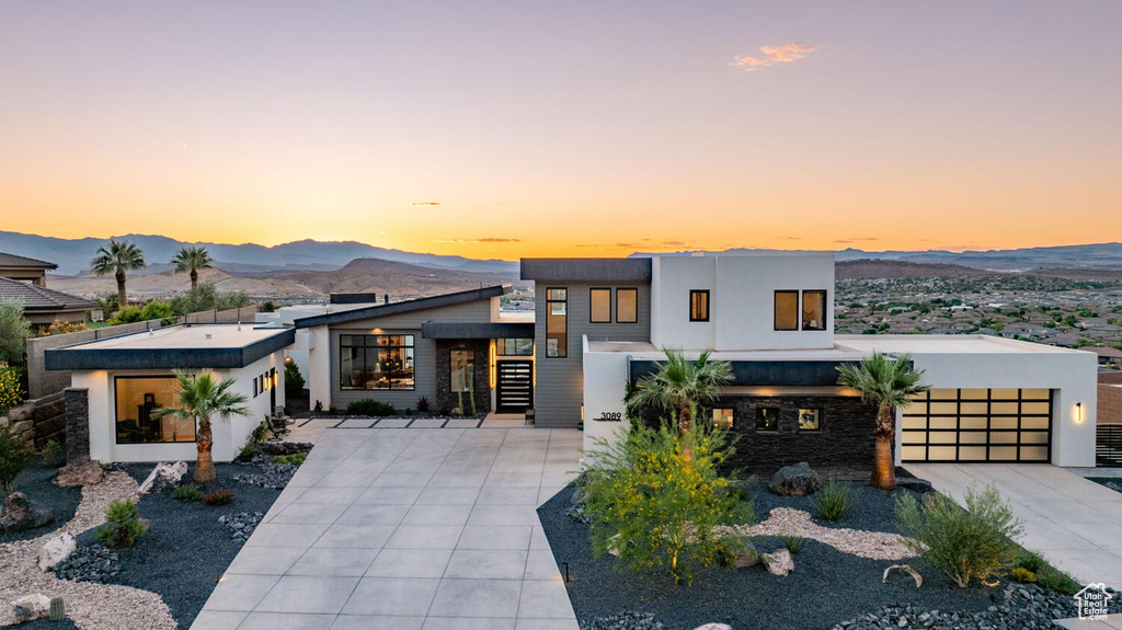 Contemporary home with a mountain view, concrete driveway, stucco siding, and a garage