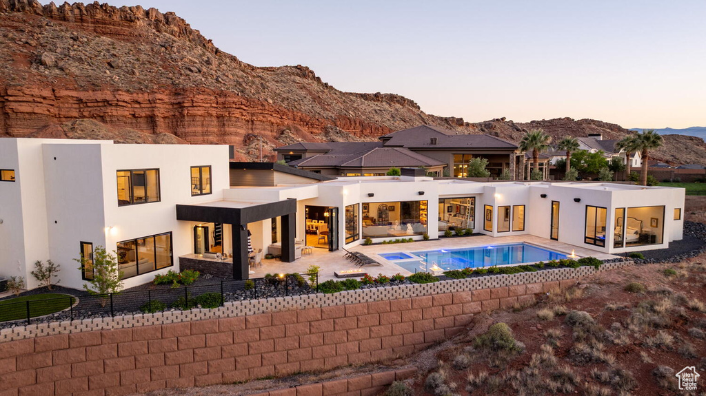 Back of house at dusk featuring an outdoor hangout area, stucco siding, a mountain view, and a patio area