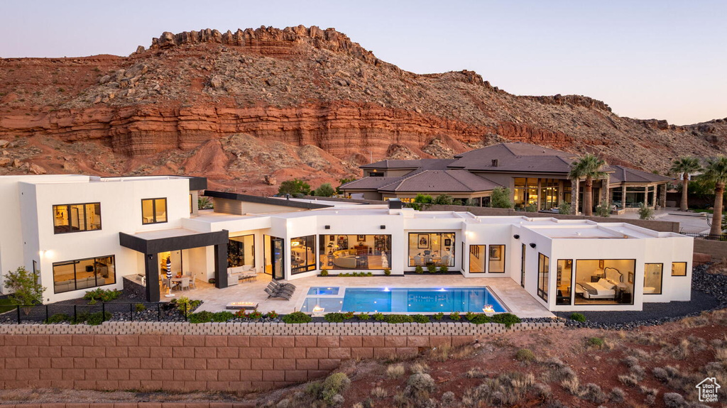 Back of property featuring stucco siding, a mountain view, a patio area, and an outdoor pool