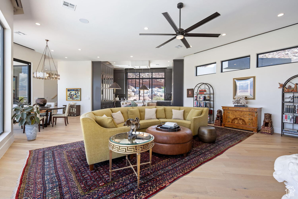 Living area with a chandelier, light wood finished floors, ceiling fan, and recessed lighting