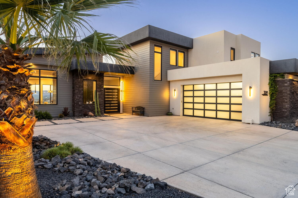 Contemporary home featuring concrete driveway, an attached garage, and stucco siding