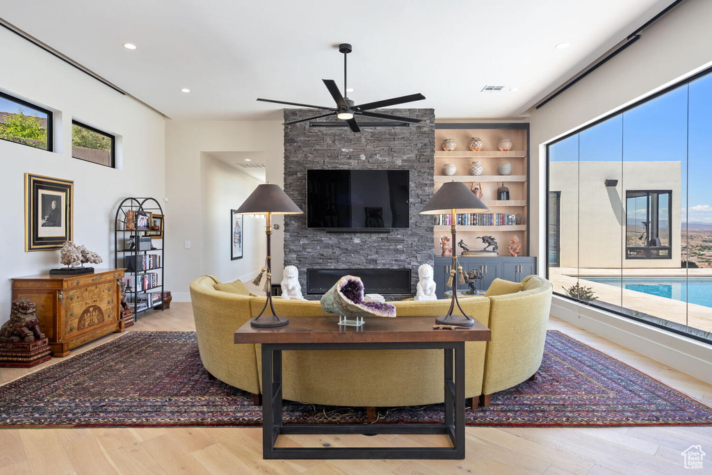 Living room with a ceiling fan, a fireplace, wood finished floors, and recessed lighting
