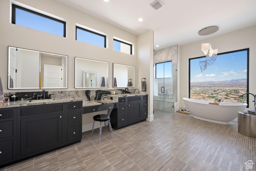 Full bath with double vanity, a stall shower, a freestanding tub, and recessed lighting