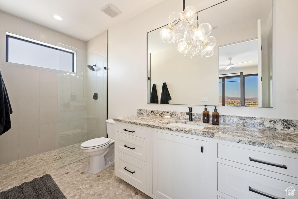 Bathroom with healthy amount of natural light, walk in shower, vanity, and ceiling fan