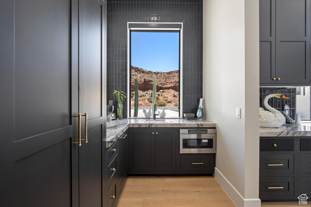 Kitchen with light stone countertops, light wood-style floors, and oven