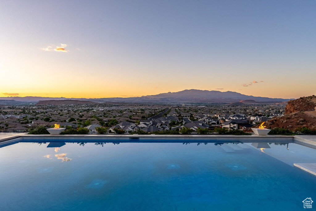 Pool at dusk featuring a mountain view and an outdoor pool