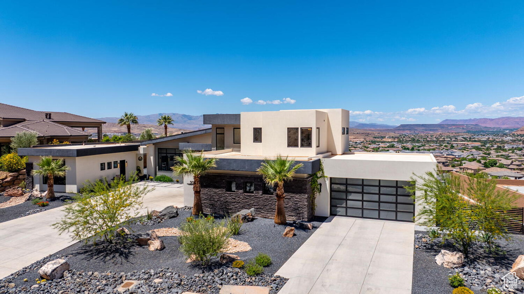 View of front of home featuring stucco siding, a mountain view, concrete driveway, and an attached garage