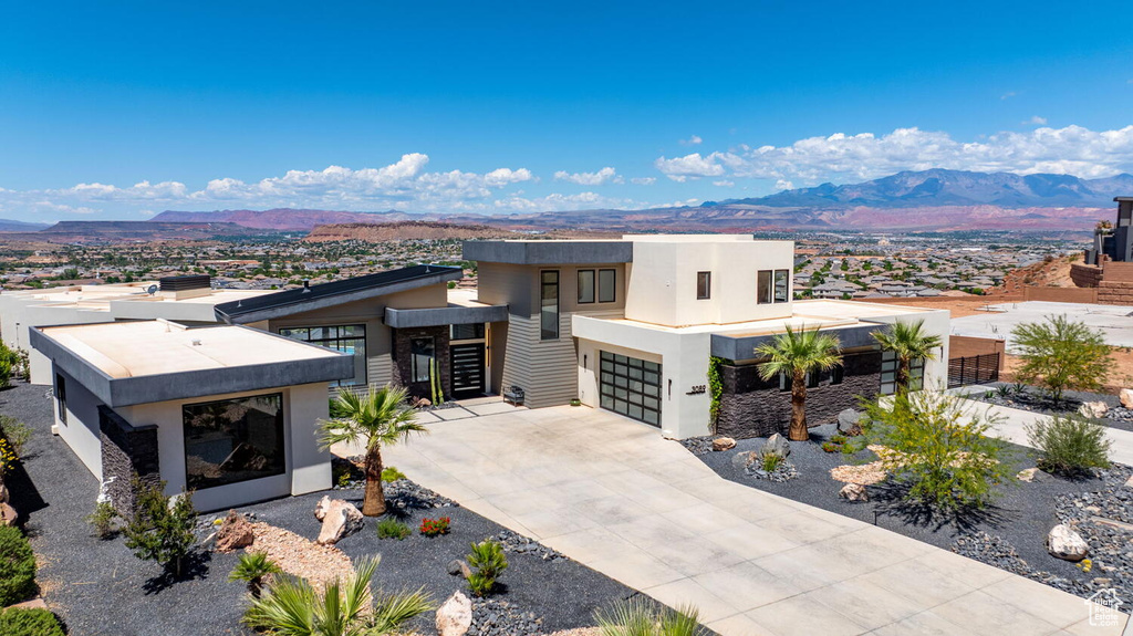 Contemporary house featuring a mountain view, stucco siding, a garage, and driveway
