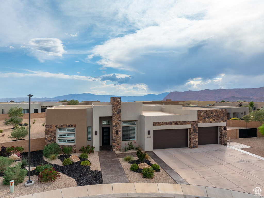 Southwest-style home with a mountain view, stucco siding, driveway, and a garage