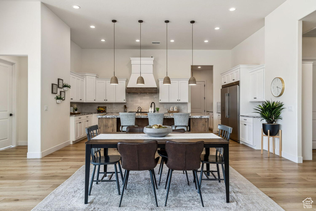 Dining room with light wood-style floors, recessed lighting, and a towering ceiling