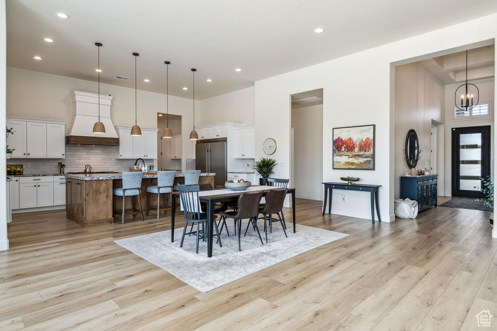 Dining space with recessed lighting, light wood-style floors, a chandelier, and a towering ceiling