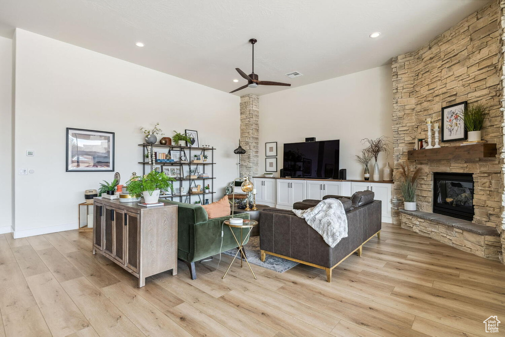 Living room featuring a ceiling fan, light wood-style floors, a stone fireplace, and recessed lighting