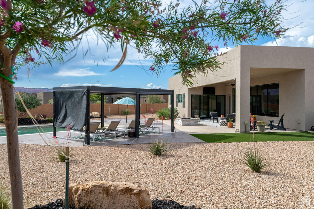 Back of property featuring stucco siding, a ceiling fan, an outdoor fire pit, a patio area, and a gazebo