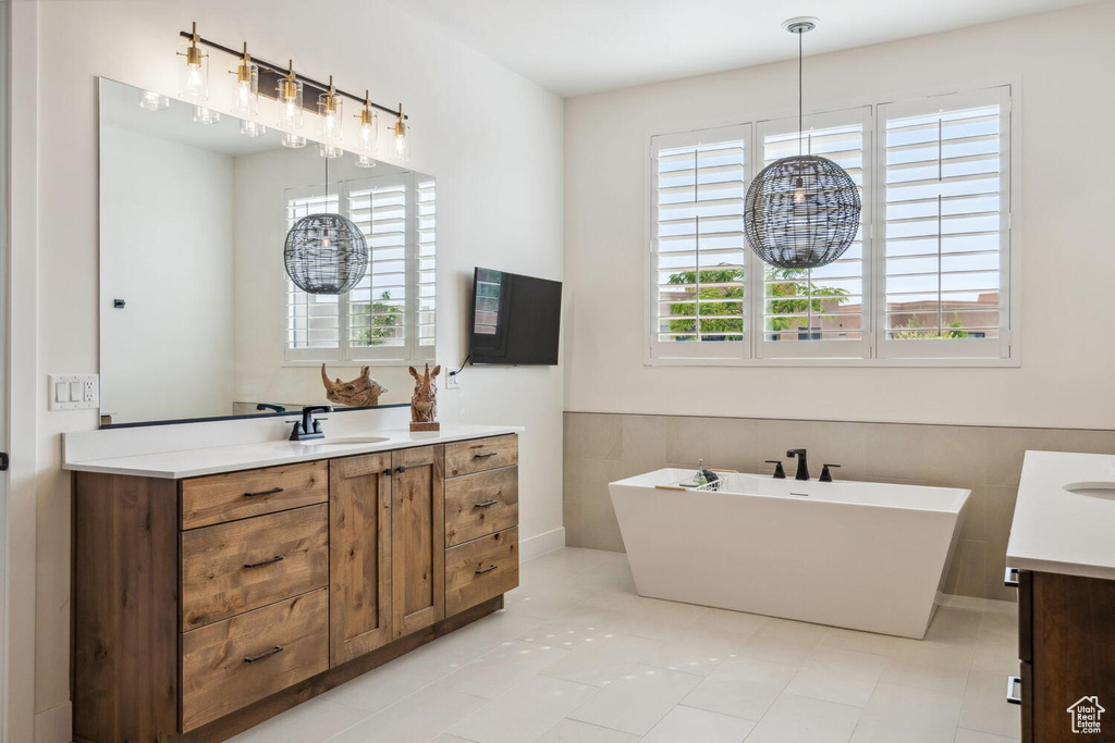 Bathroom with vanity, a freestanding bath, and tile patterned flooring