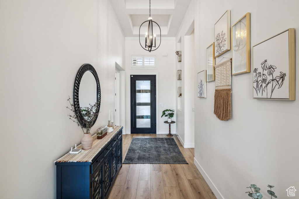Entrance foyer with light wood-type flooring, a high ceiling, and a chandelier