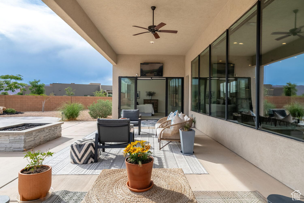 View of patio / terrace with ceiling fan and an outdoor living space with a fire pit