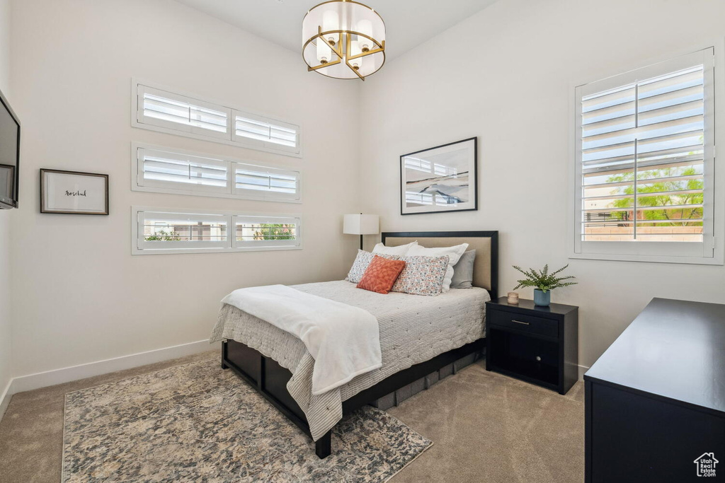 Carpeted bedroom featuring a chandelier and baseboards